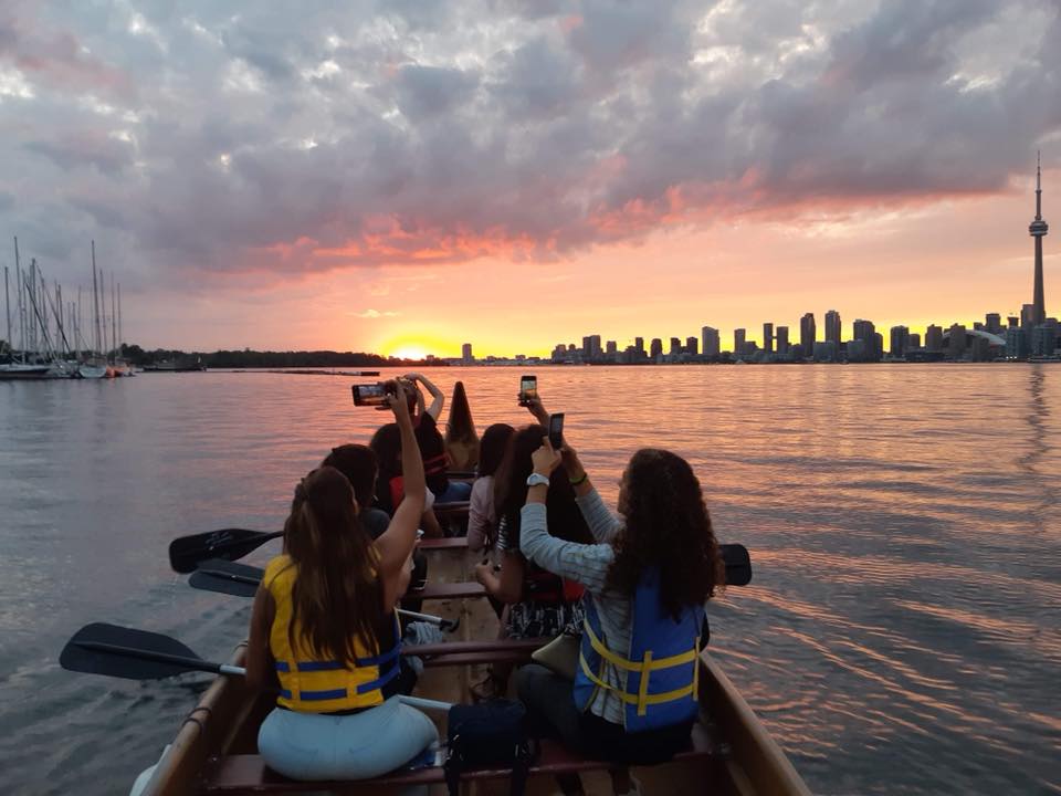 while paddling in a group, taking picturesque scene of the sun setting behind the city is a must do activity in toronto