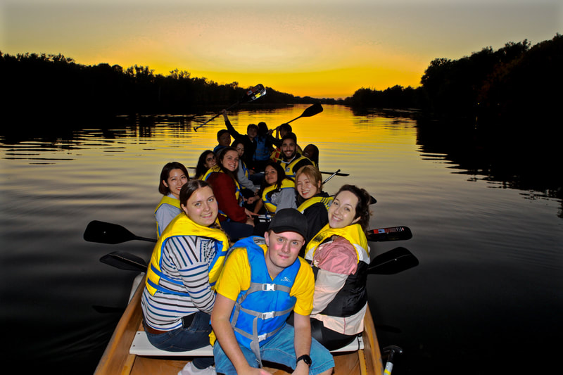 a group of paddlers is enjoying the sunset on the toronto islands while paddling big voyageur canoe in the lagoons