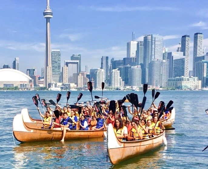 paddles up as students are cheering at their arrival by canoes to the Toronto Harbour.